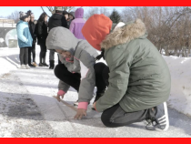 Students outside in winter on looking at something on sidewalk